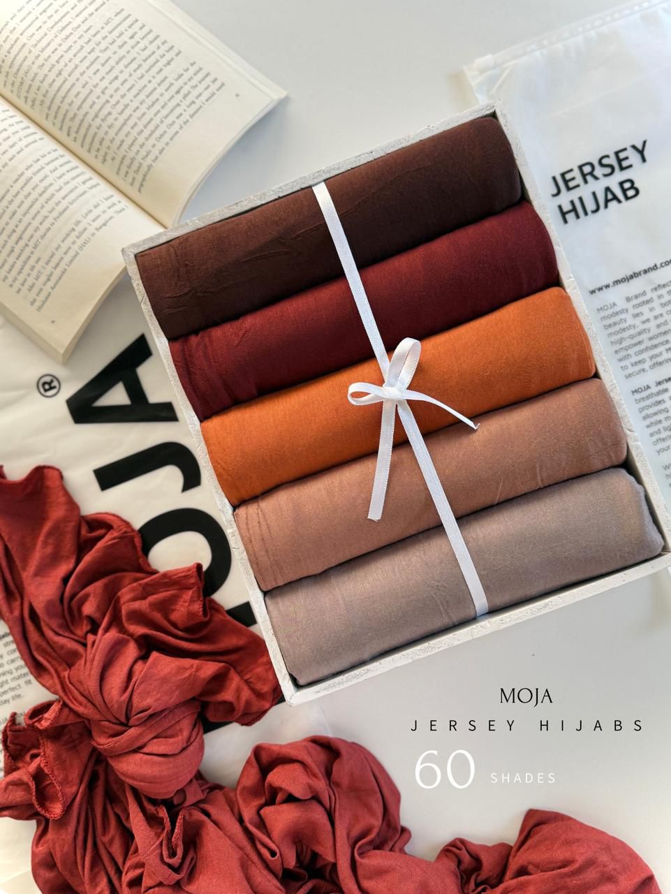 Set of jersey hijabs in various colors tied with a white ribbon, displayed in a box with 'MOJA' branding.